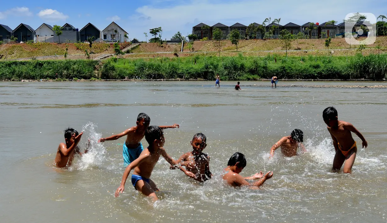 Anak-anak bermain pada aliran Sungai Cisadane di kawasan Keranggan, Setu, Tangerang Selatan, Banten, Minggu (20/3/2022). Cuaca panas terik dimanfaatkan mereka untuk berendam sambil bermain. (merdeka.com/Arie Basuki)