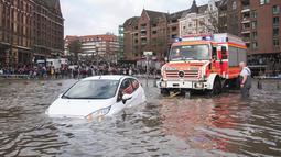 Sebuah mobil diselamatkan dari air banjir oleh pemadam kebakaran setelah badai di Hamburg, Jerman, Minggu (30/1/2022).Badai musim dingin yang kuat melanda Eropa utara selama akhir pekan. (Daniel Bockwoldt/dpa via AP)