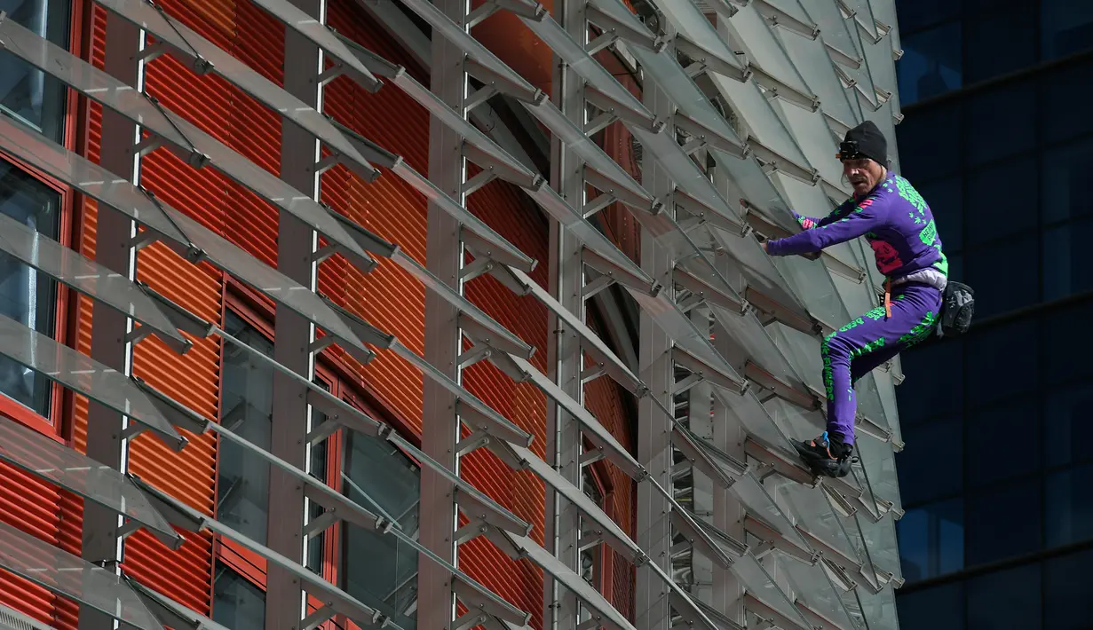 Pendaki pencakar langit, Alain Robert, yang juga dikenal sebagai 'Spiderman Prancis' memanjat Menara Agbar setinggi 144 meter di Barcelona, Rabu (4/3/2020). Aksi yang dilakukan tanpa menggunakan alat pengaman itu sebagai bentuk protes terhadap kepanikan atas epidemi virus corona. (LLUIS GENE/AFP)
