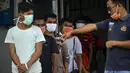 Seorang pejabat Urusan Kelautan dan Perikanan Indonesia (R) berdiri di sebelah nelayan Myanmar yang menunggu untuk dideportasi setelah ditahan selama delapan bulan di Banda Aceh (5/8/2020). (AFP Photo/Chaideer Mahyuddin)