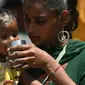 Seorang ibu membantu putrinya untuk minum air pada suatu hari di musim panas di Amritsar pada tanggal 25 April 2024. (Narinder NANU/AFP)