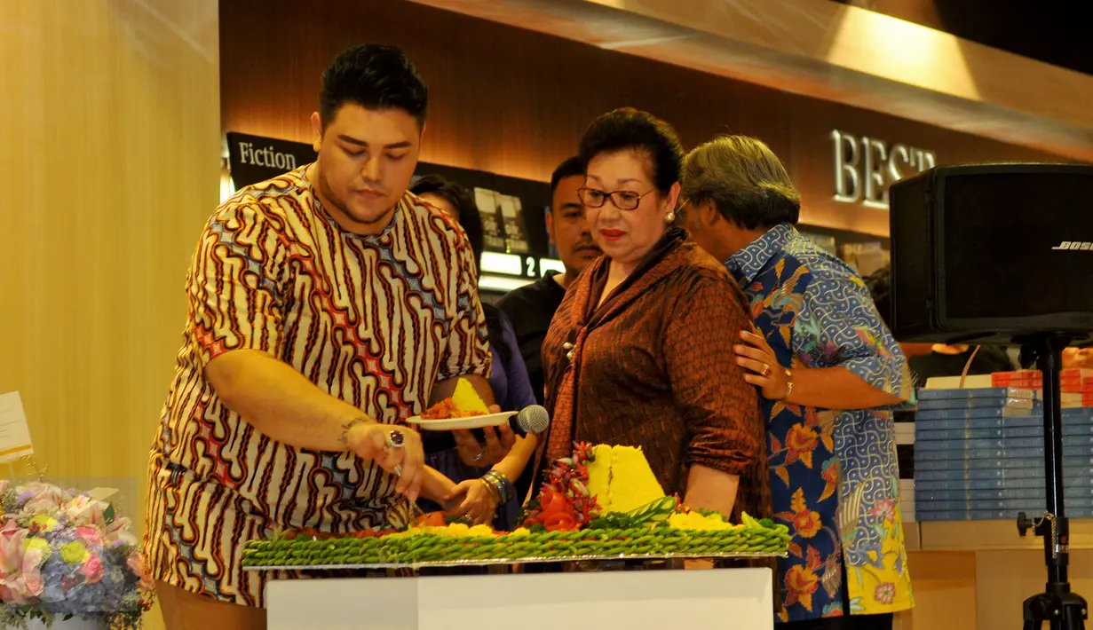 Perancang busana Ivan Gunawan memotong tumpeng saat acara peluncuran buku perdananya 'Aku Berkarya Dengan Cinta', Jakarta, Rabu (11/11). Ivan merilis buku untuk memperingati 10 tahun karirnya di bidang fashion. (Liputan6.com/Faisal R Syam)
