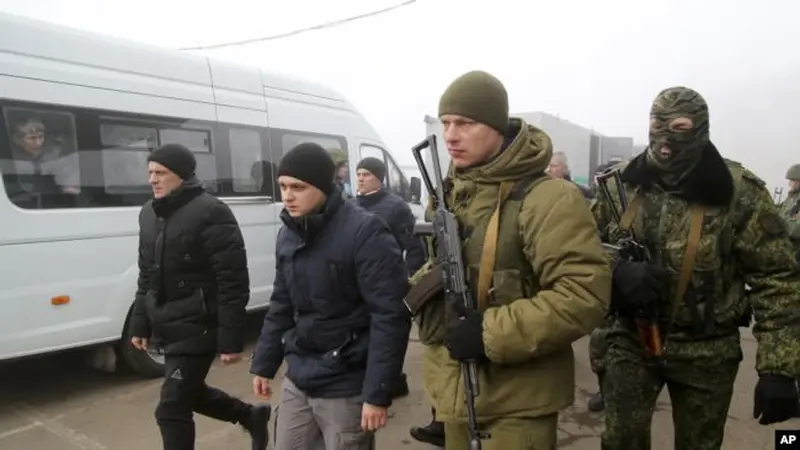 Tawanan perang asal Ukraina dikawal tentara-tentara kelompok separatis dukungan Rusia, berjalan ke bus-bus untuk proses pertukaran tahanan di Horlivka, timur Ukraina, 29 Desember 2019.