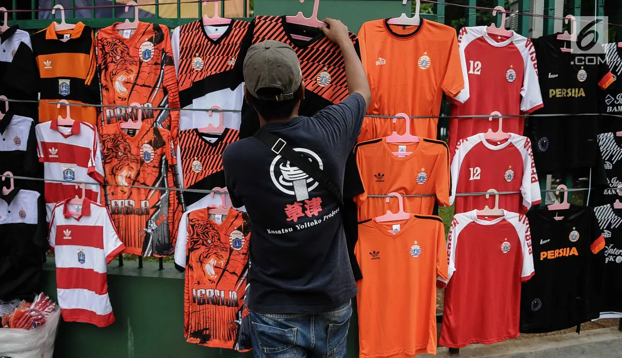 Pedagang merapikan atribut Persija di kawasan Senayan, Jakarta, Minggu (9/12). Pedagang menjual aksesoris dan atribut Persija seperti baju, bendera, dan syal dengan kisaran harga Rp.50.000 - Rp. 100.000. (Liputan6.com/Faizal Fanani)