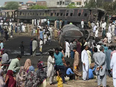 Warga berkumpul di dekat lokasi kecelakaan antara kereta penumpang dengan kereta tangki minyak di Distrik Sheikhupura, Punjab, Selasa (28/3). Sedikitnya dua orang termasuk masinis kereta tewas dalam kejadian tersebut. (AFP Photo / Ludovic Marin)