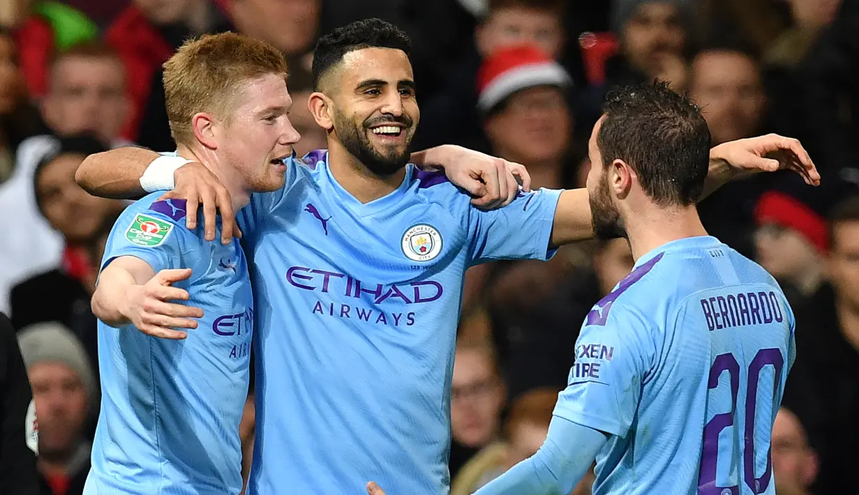 Gelandang Manchester City, Riyad Mahrez (tengah) berselebrasi dengan rekannya Kevin De Bruyne dan Bernardo Silva usai mencetak gol ke gawang Manchester United pada pertandingan leg pertama semifinal Piala Liga Inggris di Old Trafford, Rabu (8/1/2020). City menang 3-1 atas MU. (AFP/Paul Ellis)