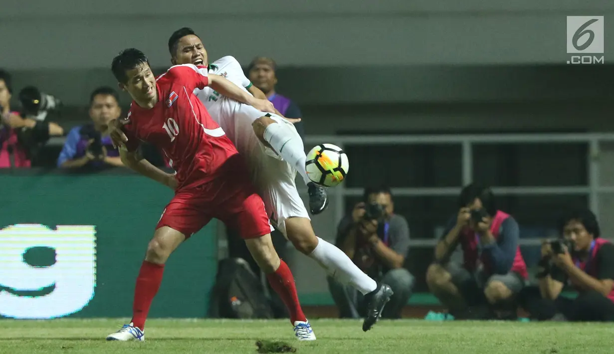 Pemain belakang Indonesia U-23, Ricky Fajrin S (kanan) berebut bola dengan pemain Korea Utara, Jo Sol Song pada laga PSSI Anniversary Cup 2018 di Stadion Pakansari, Kab Bogor, Senin (30/4). Babak pertama imbang 0-0. (Liputan6.com/Helmi Fithriansyah)