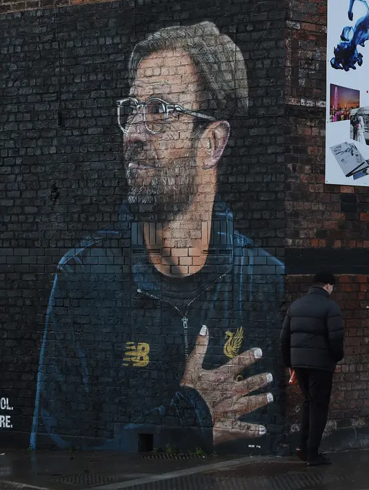 Warga melintas dekat mural pelatih klub Liverpool, Jurgen Klopp di pusat kota Baltic Triangle, Liverpool, Senin (10/12). Banyak yang menyambut pembuatan mural itu namun tidak sedikit pula yang mencibir, termasuk suporter klub Everton. (Paul ELLIS / AFP)