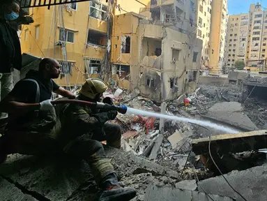 Petugas pemadam kebakaran berupaya memadamkan api di sebuah bangunan setelah serangan udara Israel di distrik Haret Hreik di pinggiran selatan Beirut pada 16 November 2024. (Foto oleh AFP)