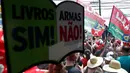 Sebuah tanda bertuliskan "Buku Ya, Tidak Senjata" terlihat saat mantan presiden Brasil (2003-2010) dan calon presiden dari Partai Buruh (PT) berhaluan kiri, Luiz Inacio Lula da Silva (kanan), menyampaikan pidato saat kampanye di Sao Mateus, Negara Bagian Sao Paulo, Brasil, Senin (17/10/2022). Lula da Silva dan presiden Jair Bolsonaro akan menghadapi putaran kedua pemilihan presiden pada 30 Oktober, dengan ekspektasi persaingan ketat mendorong kedua belah pihak untuk mengintensifkan kampanye di putaran kedua. (Miguel SCHINCARIOL / AFP)