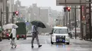 Seseorang berjalan di tengah hujan di depan sebuah stasiun di Shizuoka, sebelah barat Tokyo, Sabtu (13/8/2022). Badai Tropis Meari mengeluarkan hujan lebat di barat daya Jepang saat menuju ke utara menuju ibu kota Tokyo, menurut pejabat cuaca Jepang. (Kyodo News via AP)