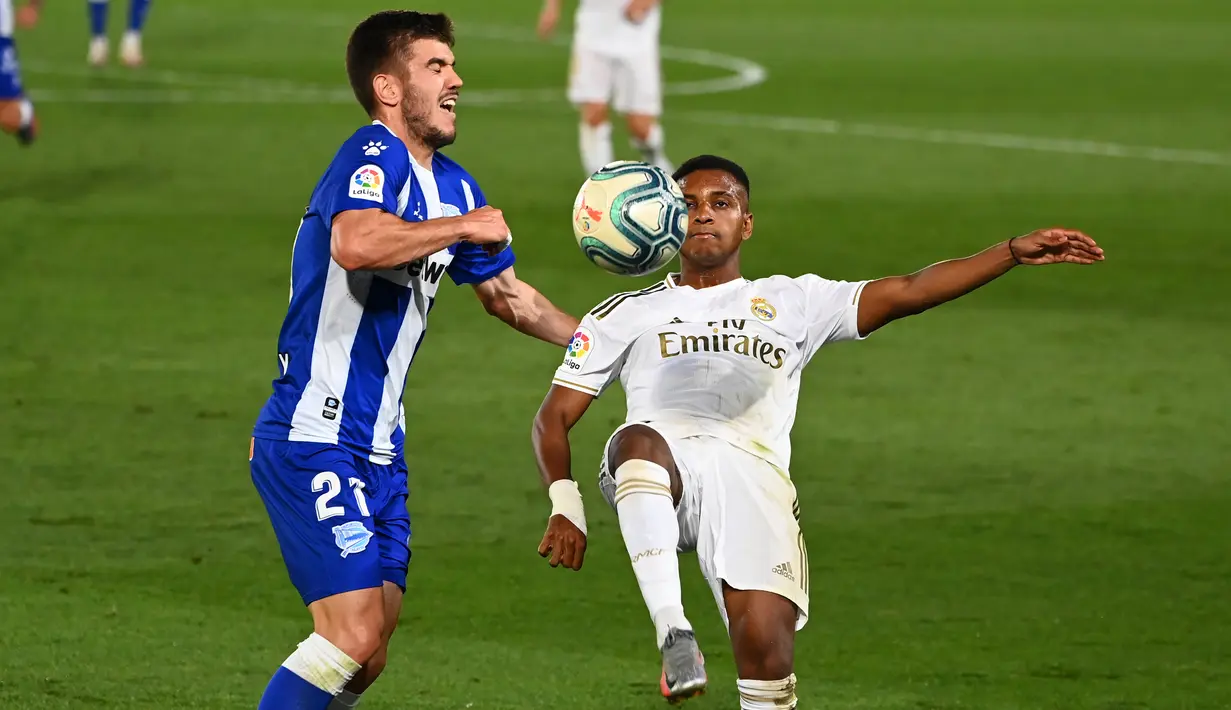 Penyerang Real Madrid, Rodrygo, berebut bola dengan bek Alaves, Martin Aguirregabiria, pada laga lanjutan La Liga pekan ke-35 di Stadion Alfredo di Stefano, Sabtu (11/7/2020) dini hari WIB. Real Madrid menang 2-0 atas Alaves. (AFP/Gabriel Bouys)