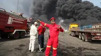 Pemadam kebakaran bekerja saat asap hitam mengepul di langit setelah ledakan dahsyat mengguncang pelabuhan dekat kota selatan Bandar Abbas, Iran, Sabtu (26/4/2025) (Mohammad Rasoul Moradi/IRNA via AP Photo)