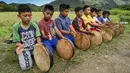 Sejumlah anak laki-laki memainkan rebana tradisional saat mengambil bagian dalam tari Rapa'i Geleng di sepanjang sawah di desa ekowisata Nusa, Lhoknga, Provinsi Aceh, 26 September 2021. Rapa'i Geleng adalah tarian yang berasal dari Aceh bagian selatan tepatnya Manggeng. (CHAIDEER MAHYUDDIN/AFP)