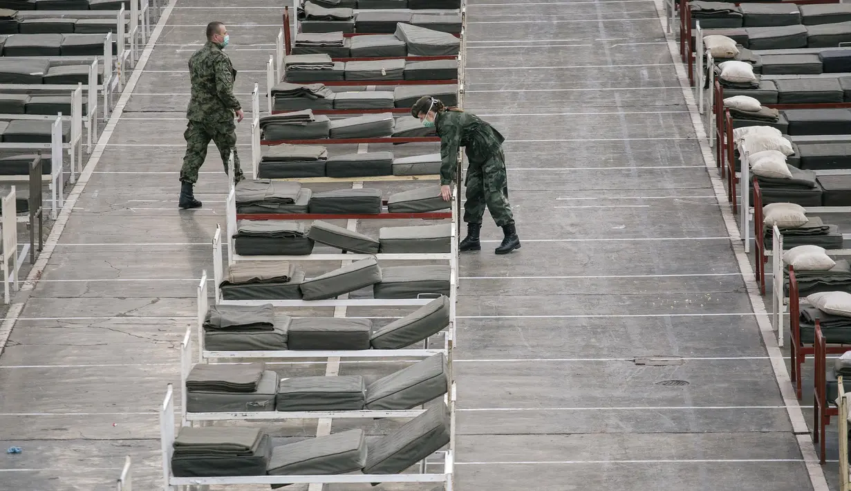 Tentara Serbia menyiapkan tempat tidur di dalam aula Belgrade Fair yang diubah menjadi rumah sakit sementara virus Corona, Selasa (24/3/2020). Rumah sakit tersebut direncanakan menampung 3000 tempat tidur untuk  menangani pasien dengan gejala ringan corona Covid-19. (Vladimir Zivojinovic/AFP)