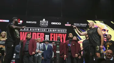 Petinju asal Inggris, Tyson Fury (kanan) menunjuk ke arah Deontay Wilder dari AS saat melakukan penimbangan berat badan untuk pertandingan tinju kelas berat WBC di Las Vegas (21/2/2020).  Tyson Fury dan Deontay Wilder akan bertanding di MGM Arena. (AP Photo/Isaac Brekken)