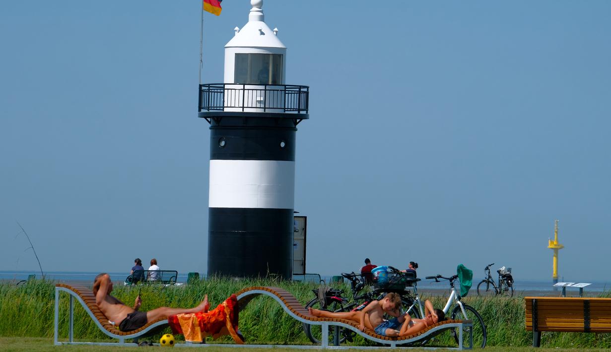 Warga berjemur saat suhu mencapai 34 derajat Celcius di dekat pantai Laut Utara di Wremen, Jerman barat (24/7/2019). Peramal cuaca memprediksi suhu tertinggi di seluruh Eropa barat yang terkena gelombang panas akan mencetak rekor suhu terbaru.  (AFP Photo/Patrik Stollarz)