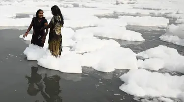 Sejumlah wanita mandi di sungai Yamuna yang tertutup busa limbah sebagai bagian dari ritual untuk festival Chhath Puja yang akan datang di New Delhi, Senin (8/11/2021). Sungai yang sangat dianggap suci oleh umat Hindu India ini dipenuhi lapisan busa karena limbah beracun. (Sajjad HUSSAIN / AFP)