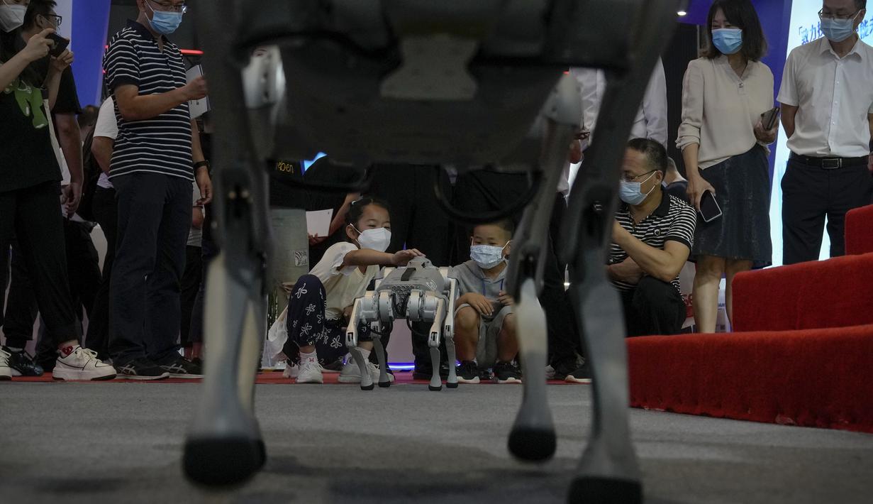 Anak-anak yang memakai masker wajah bermain dengan robot side-follow cerdas Unitree Go 1 selama Konferensi Robot Dunia di Pusat Konferensi dan Pameran Internasional Yichuang di Beijing, Kamis (18/8/2022). (AP Photo/Andy Wong)