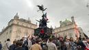 Suporter Inggris memanjat patung Eros di Piccadilly Circus saat merayakan kemenangan Inggris atas Jerman pada pertandingan babak 16 besar Euro 2020 di London, Inggris, Selasa (29/6/2021). nggris menang 2-0. (Isobel Frodsham/PA via AP)