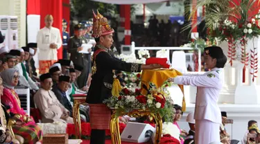 Presiden Joko Widodo (tengah) menyerahkan duplikat bendera pusaka kepada Paskibraka Tarrisa Maharani Dewi saat Upacara Peringatan Detik-detik Proklamasi Kemerdekaan ke-73 di Istana Merdeka, Jakarta, Jumat (17/8). (Liputan6.com/HO/Bian)