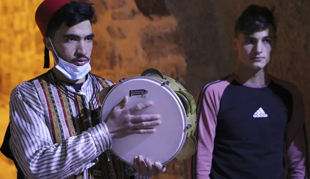 Pria Palestina yang dikenal dengan "Musaharatis" saat bertugas sebagai "penabuh drum Ramadhan" di kota tua Hebron, Tepi Barat pada 14 April 2021. Mereka menyusuri jalan-jalan kota, masuk ke gang-gang kecil untuk membangunkan umat Islam sahur selama bulan Ramadhan. (HAZEM BADER/AFP)