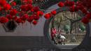 Seorang wanita membawa balita melihat lampion yang menggantung di pohon di taman Ditan di Beijing (1/2). Tahun Baru Imlek jatuh pada 16 Februari tahun ini, dengan perayaan yang berlangsung selama seminggu di China. (AFP Photo/Nicolas Asfouri)