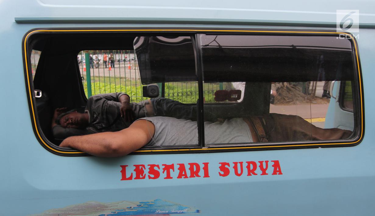Seorang sopir angkot M08 trayek Tanah Abang-Kota tertidur di dalam kendaraannya di Jalan Jatibaru, Jakarta, Kamis (22/2). Para sopir terlihat sedang menunggu rekan sopir M03 dan M10 yang juga akan ikut berunjuk rasa. (Liputan6.com/Arya Manggala)