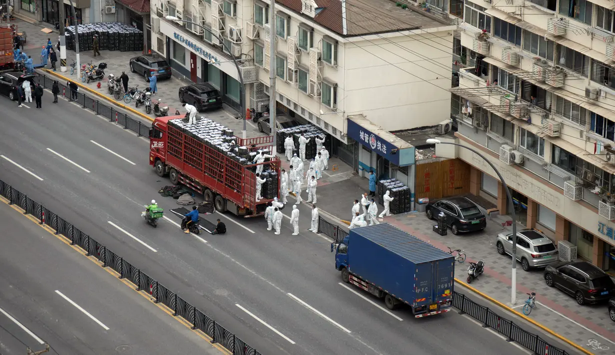 Orang-orang yang mengenakan alat pelindung diri memindahkan persediaan makanan dan kebutuhan sehari-hari untuk penduduk setempat saat lockdown tahap kedua akibat COVID-19 di Shanghai, China, Selasa (5/4/2022). (STR/AFP)