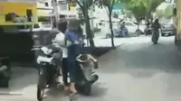 Tiga remaja menaiki sebuah sepeda motor berjenis skuter matik (skutik). Salah satu remaja terlihat menggunakan rok sekolah berwana biru.