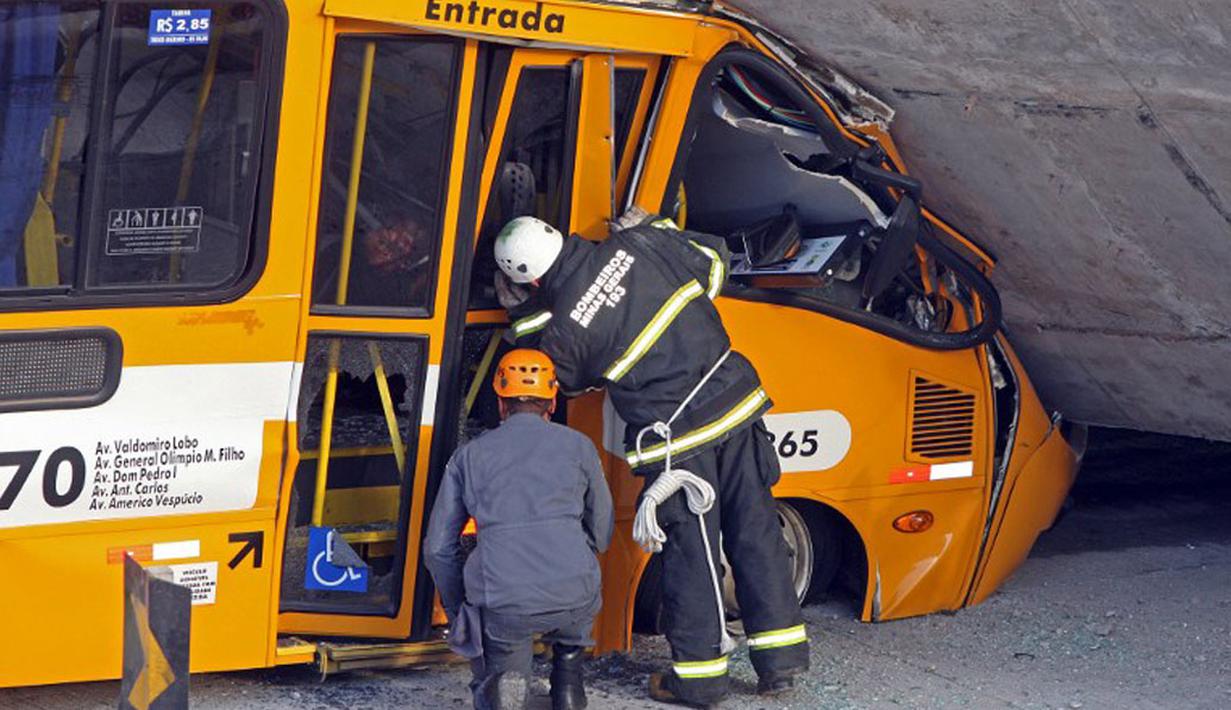 Petugas pemadam kebakaran setempat melihat kondisi sebuah bus angkutan umum yang hancur akibat tertimpa jembatan yang runtuh di di Belo Horizonte, Brasil, (3/7/2014). (AFP PHOTO/Leo Fontes)