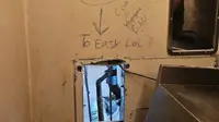 Celah di belakang toilet di dalam sel tempat para napi melarikan diri — lengkap dengan pesan ejekan yang ditulis di dinding dengan tulisan "Terlalu Gampang LoL" dengan tanda panah yang menunjuk ke celah tersebut. (AP)
