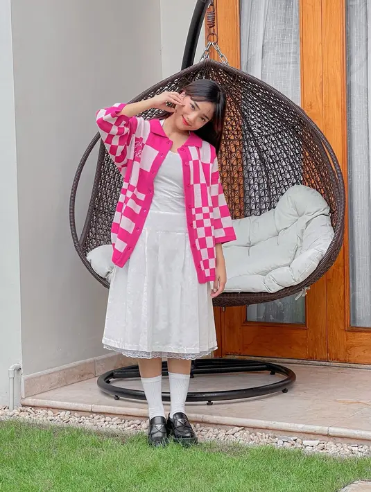 Seperti potret ini, ia tampil ala cewek kue dengan padu padan knit cardigan warna pink dengan dress renda warna putih, dan sepatu loafers Prada. [Foto: IG/@aaliyah.massaid/@fuji_an]