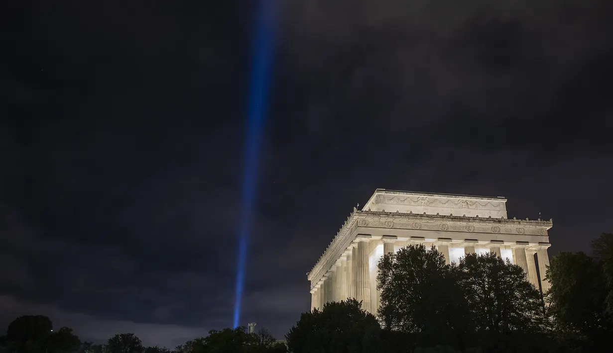 Cahaya biru terlihat saat penghormatan ringan untuk serangan 9/11 di Pentagon yang berada di samping Lincoln Memorial di Washington, DC (11/9/2020). Pertunjukan tersebut adalah bagian dari peringatan skala kecil tahun ini karena pandemi virus corona. (Tasos Katopodis / Getty Images / AFP)