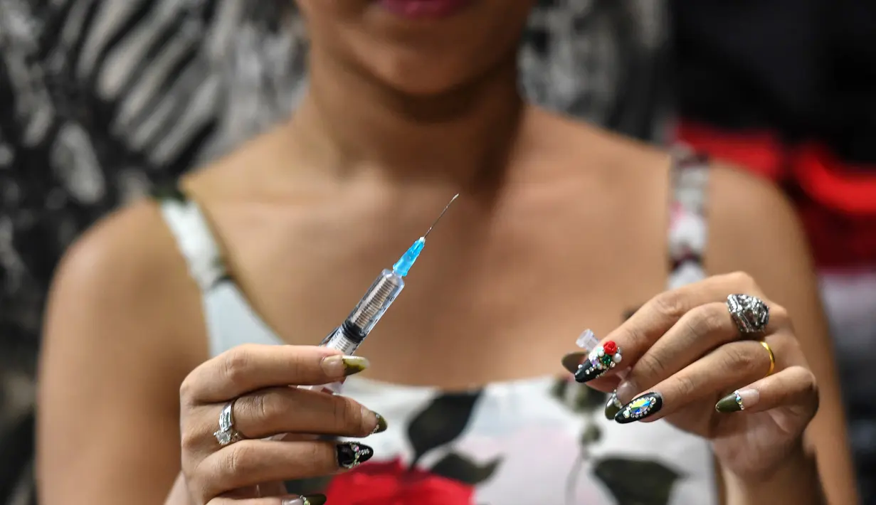Jessica Nguyen mempersiapkan dosis suntik hormon di tokonya, Ho Chi Minh, Vietnam (30/3). Pemerintah Vietnam belakangan telah merancang UU mengenai hukum yang akan memungkinkan orang untuk secara resmi mengubah jenis kelamin. (AFP Photo/Hoang Dinh Nam)