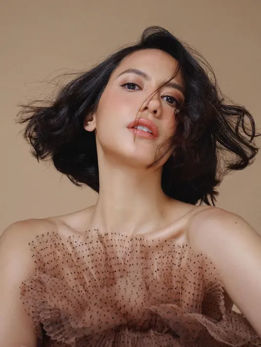 Pevita tampil dengan outfit strapless, memamerkan bahunya. Rambut pendeknya ditata mengembang bergelombang. Foto: Instagram.