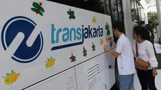 Seorang anak berkebutuhan khusus melukis bus Transjakarta di halaman Balai Kota, Jakarta, Jumat (20/4). Kegiatan tersebut dalam rangka memperingati Hari Kartini. Tema lukisan yang diangkat adalah ‘Ibuku Perempuan Tangguh’. (Liputan6.com/Arya Manggala)