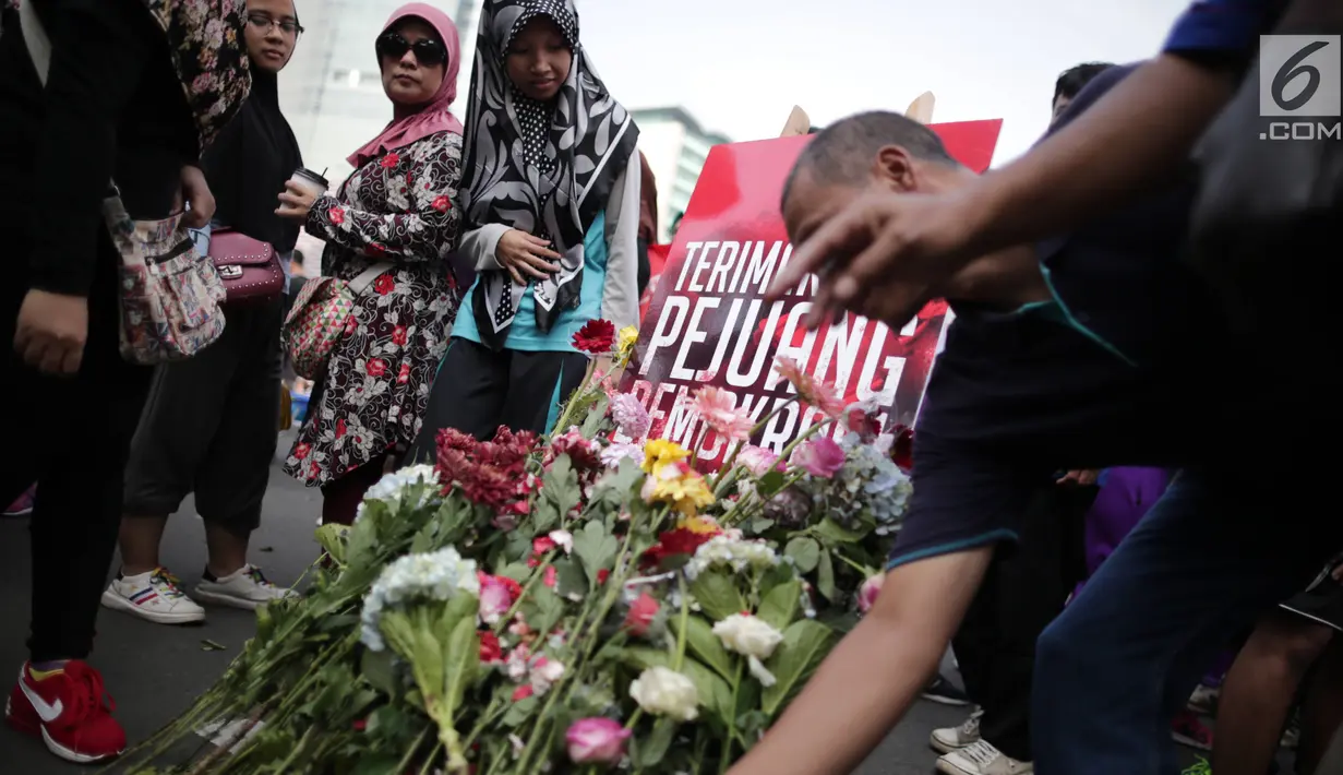 Pengunjung car free day meletakan bunga yang diberikan oleh anggota TKN Milenial Jokowi-Ma'ruf dalam kegiatan tabur bunga di Bundaran HI, Jakarta, Minggu (28/4/2019). Aksi tersebut sebagai bentuk duka atas meninggalnya 272 petugas KPPS dalam Pemilu 2019. (Liputan6.com/Faizal Fanani)