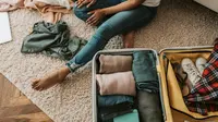 Ilustrasi packing baju, koper. (Foto oleh Vlada Karpovich: https://www.pexels.com/id-id/foto/orang-wanita-duduk-sepatu-7365311/)