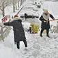 Orang-orang menyekop salju dari jalan layang setelah hujan salju lebat di Yantai, di provinsi Shandong, China timur pada 20 Desember 2023. Suhu di kota-kota di China utara mencapai rekor terendah pada hari Rabu. (STR / AFP)