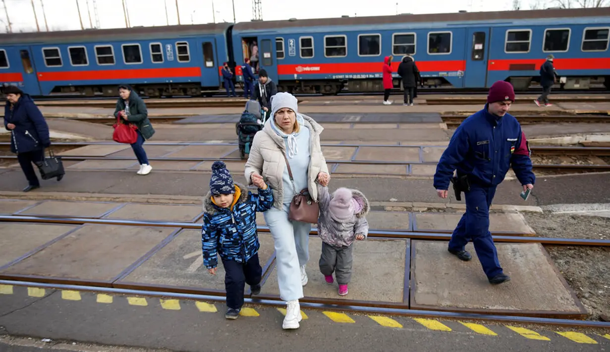 Seorang wanita memegang tangan anak-anak saat turun dari kereta api dari Ukraina di stasiun di Zahony, Hungaria, 8 Maret 2022. PBB mengatakan, serangan gencar Rusia telah memaksa lebih dari 2 juta orang meninggalkan Ukraina. (AP Photo/Darko Vojinovic)