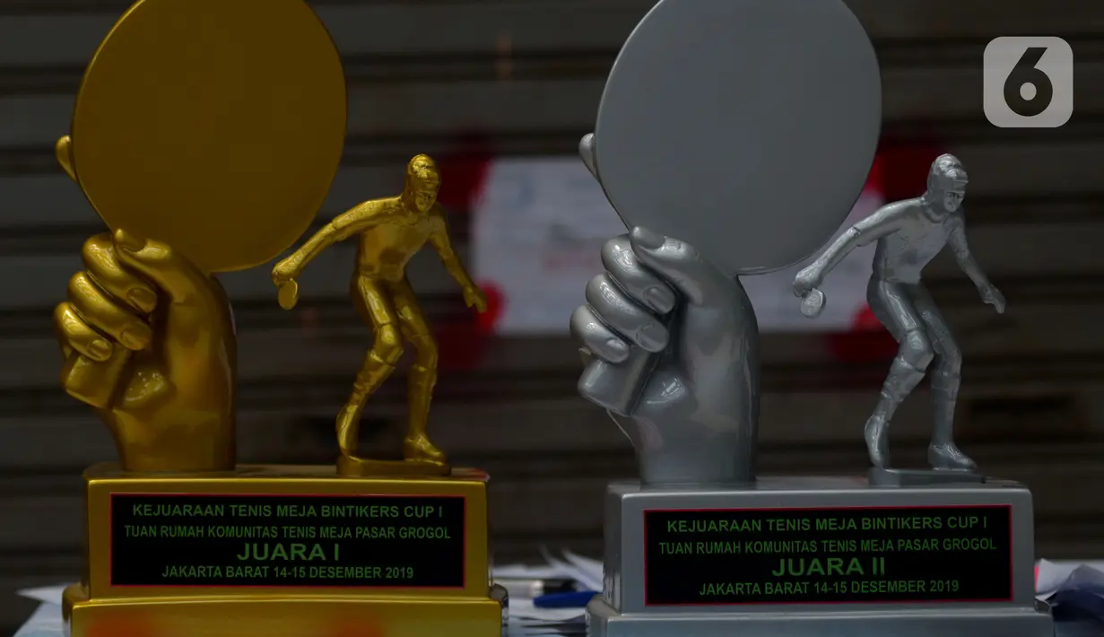 Piala kejuaraan Bintikers Cup Tenis Meja dipajang saat berlangsungnya turnamen tenis meja amatir di Pasar Grogol, Jakarta, Sabtu (14/12/2019). Turnamen Bintikers Cup Tenis Meja diikuti 125 orang perwakilan pedagang pasar se-Jabodetak dan luar Jakarta seperti Surabaya. (merdeka.com/Imam Buhori)