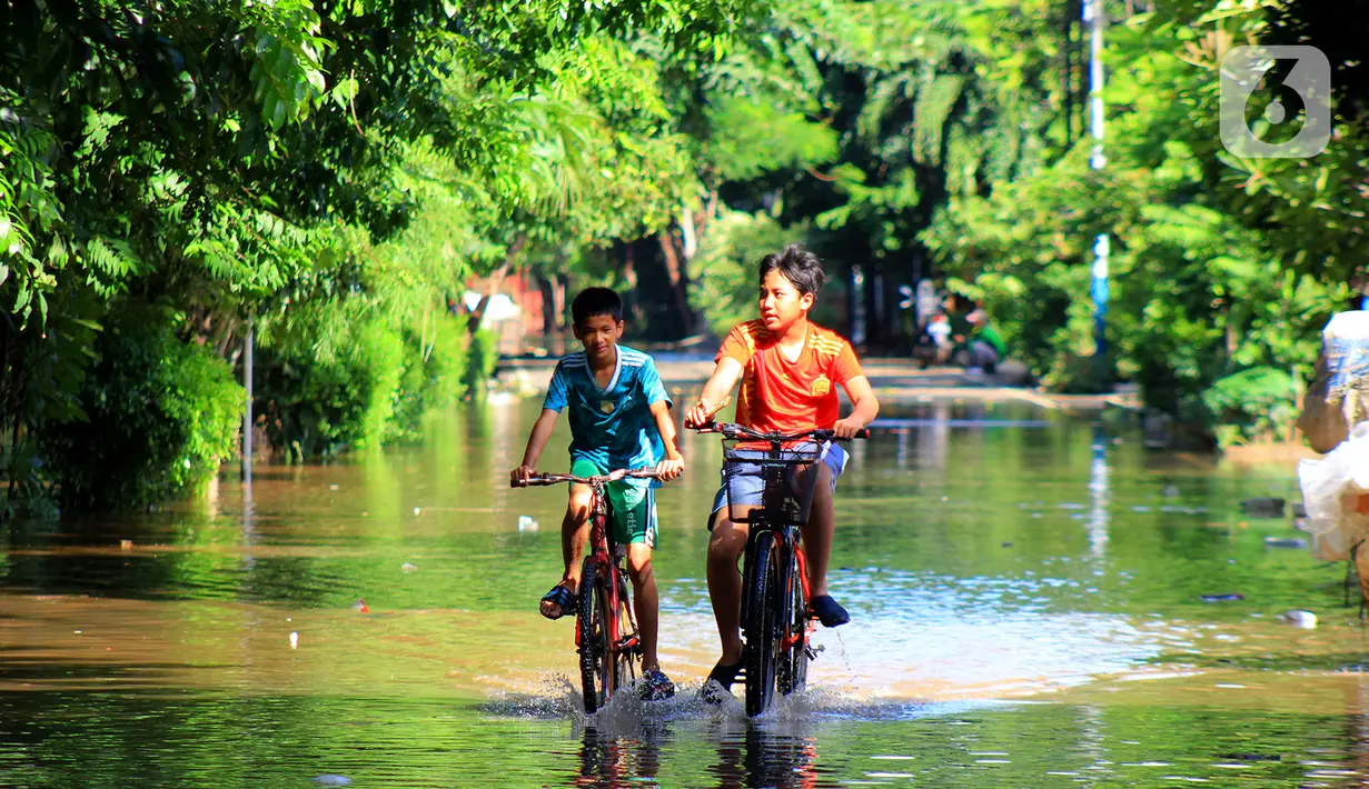 Dua anak sedang bermain sepeda melintasi banjir di kawasan Jalan Raya Kayu Putih, Jakarta, Minggu (23/2/2020). Usai hujan deras sejak Sabtu (22/2) malam hingga dini hari menyebabkan banjir di Jalan Raya Kayu Putih, Jakarta, Minggu (23/2). (merdeka.com/Magang/Muhammad Fayyadh)