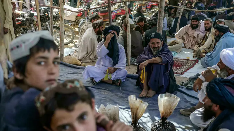 Penjual opium dan pembeli mengobrol tentang teh hijau di sekitar karung opium dan hashish di sebuah pasar opium di Kandahar, Afghanistan (BULENT KILIC / AFP)