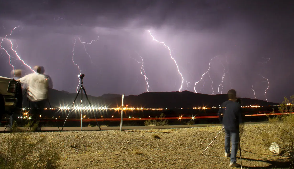 Fotografer saat mengabadikan kilatan petir yang terlihat dari bandara Daggett, Barstow, California, Rabu (1/7/2015) waktu setempat. Cuaca ekstrim yang terjadi mengakibatkan hujan badai di kawasan tersebut. (REUTERS/Gene Blevins)
