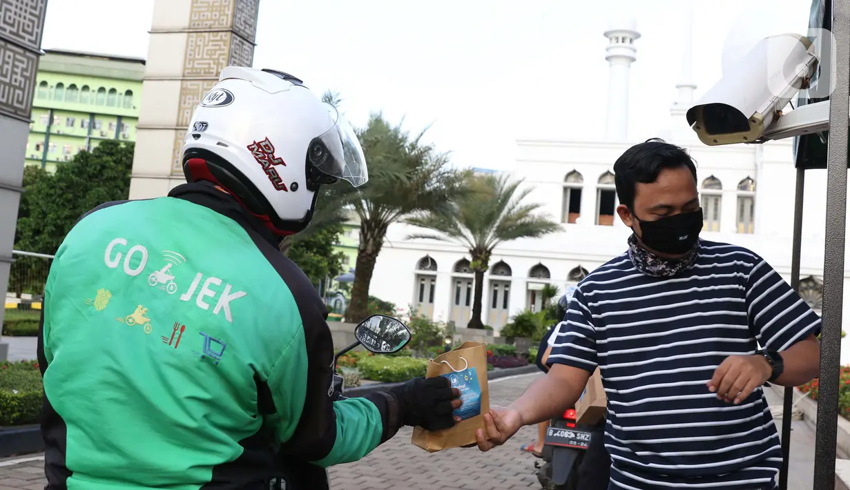 Petugas membagikan takjil dengan sistem drive thru di Masjid Agung Al-Azhar, Jakarta, Selasa (5/5/2020). Selama Ramadan, pengurus Masjid Agung Al-Azhar membagikan 300 takjil per hari buat pengendara yang melintasi lokasi tersebut. (Liputan6.com/Helmi Fithriansyah)