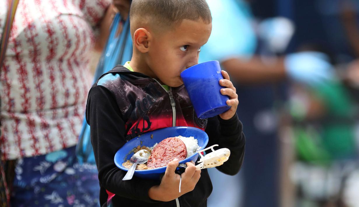 Seorang anak pengungsi Venezuela makan di tempat penampungan Divina Providencia, La Parada, Cucuta, Kolombia, Senin (18/2). Tempat penampungan ini melayani sekitar 4.500 makan siang per hari. (AP Photo/Fernando Vergara)