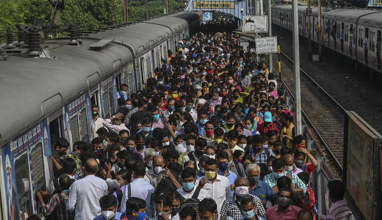 Komuter berjalan di sepanjang peron setelah keluar dari kereta lokal pinggiran kota di Kolkata, India, Senin (1/11/2021). Layanan kereta api kembali normal setelah menerapkan pembatasan yang diberlakukan sebelumnya untuk mengekang penyebaran corona Covid-19. (DIBYANGSHU SARKAR/AFP)