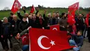 Warga membentangkan bendera sebagai dukungannya terhadap tentara Turki yang sedang memerangi milisi Kurdi di Suriah, Kilis, Turki, Jumat (26/1).  Pasukan Demokratik Suriah mengatakan serangan Turki telah menewaskan 100 orang. (AP Photo/Lefteris Pitarakis)
