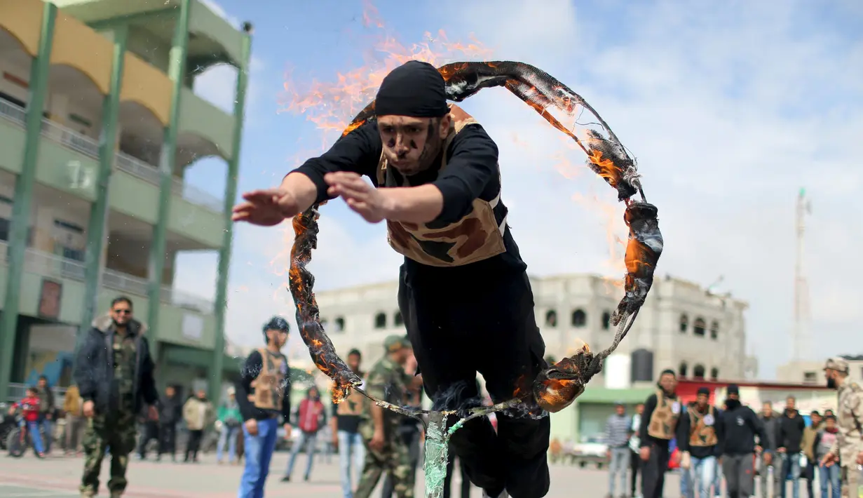 Pelajar melompat masuk ke dalam lingkaran api selama latihan militer di sebuah sekolah, Rafah, Jalur Gaza, Senin (28/3). Para pelajar dengan semangat diajarkan beberapa gerakan militer. (REUTERS / Ibraheem Abu Mustafa)